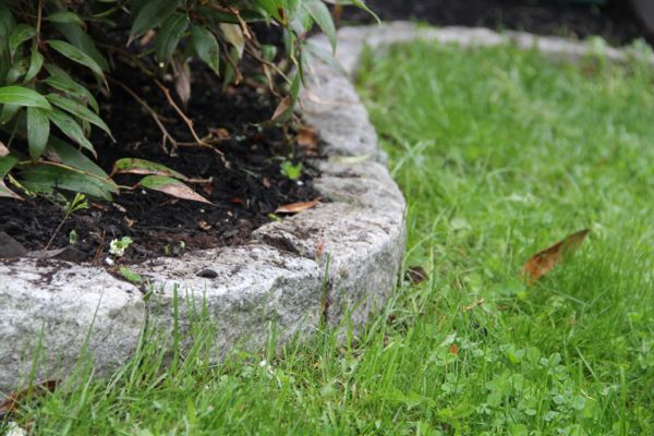 Granite cobblestone border separating a mulched bed from a green lawn